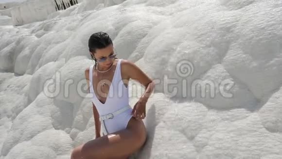 穿着白色泳衣的性感年轻女子站在白色的山上视频的预览图
