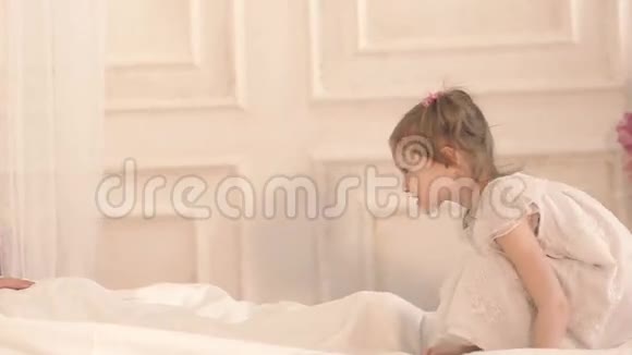 可爱的小女孩在床上跳到父亲身边拥抱他视频的预览图
