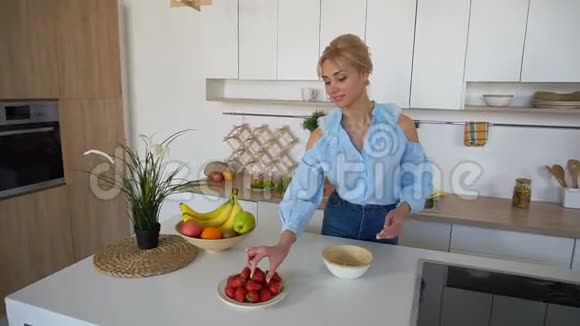 美丽的女性家庭主妇微笑着准备健康的早餐早上站在现代明亮厨房的餐桌前视频的预览图