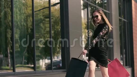 可爱的年轻购物女人拿着五颜六色的购物袋在城市里散步视频的预览图