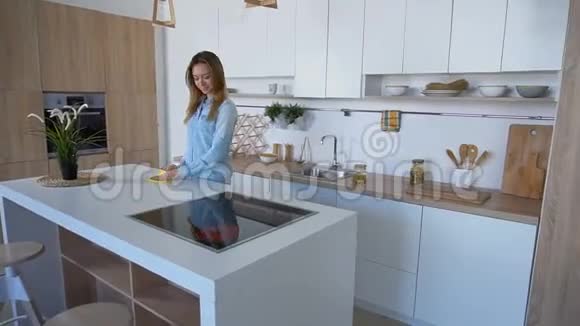 漂亮漂亮的女性家庭主妇白天清理厨房表面站在现代厨房的中间视频的预览图