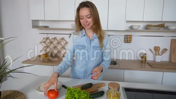 现代女孩选择从哪种蔬菜中准备沙拉微笑成相机站在厨房的中央视频的预览图