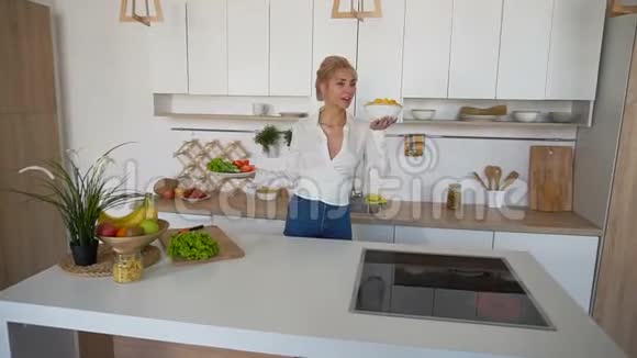 可爱的女人手里拿着盘子检查熟食的新鲜度站在现代厨房的中间视频的预览图