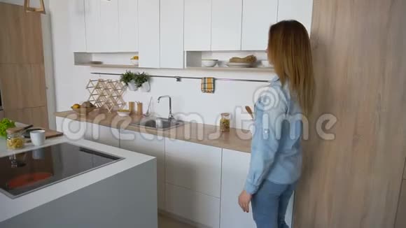 有魅力的女人走进厨房享受着提神的咖啡站在厨房的中央在厨房的餐桌上视频的预览图