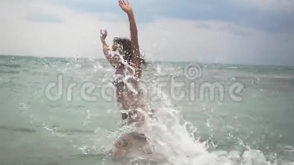谭欢喜的年轻女子跑进大海溅起浅浪在海洋中游泳暑假慢动作视频的预览图