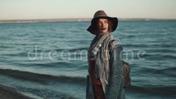 美丽的年轻女子穿着秋装在夕阳下漫步在沙滩上视频的预览图