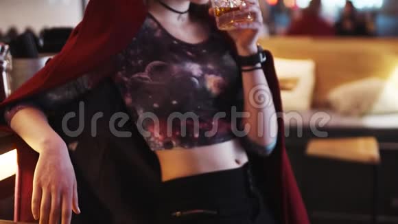 一个穿着酒精鸡尾酒的服装的迷人的年轻女子在酒吧旁喝着鸡尾酒然后转向相机给人一种欢快的感觉视频的预览图