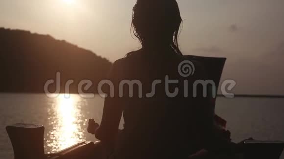 女孩冥想坐在船上的洛托斯的姿态在海上而度假在惊人的日落1920x1080视频的预览图