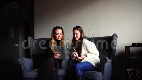 优雅的女性朋友在晚餐时使用平板电脑相互交流坐在灰色的椅子上坐在时尚的咖啡馆里视频的预览图