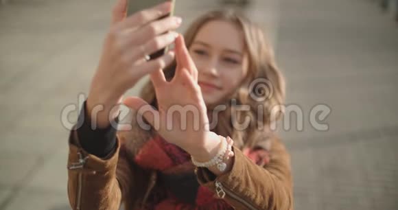 年轻女子在阳光城街道用手机自拍视频的预览图