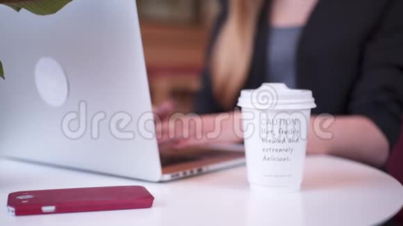 穿着黑色夹克的年轻可爱的女人坐在咖啡馆里她正在喝咖啡和她一起工作视频的预览图