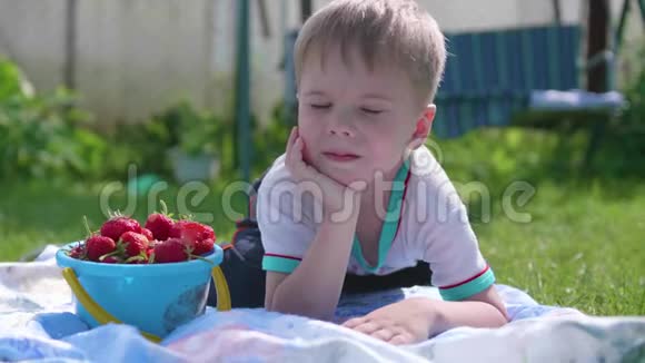 一个小男孩在炎热的夏天躺在草坪上这个孩子很有趣很活跃地度过了他们的闲暇时间快乐视频的预览图