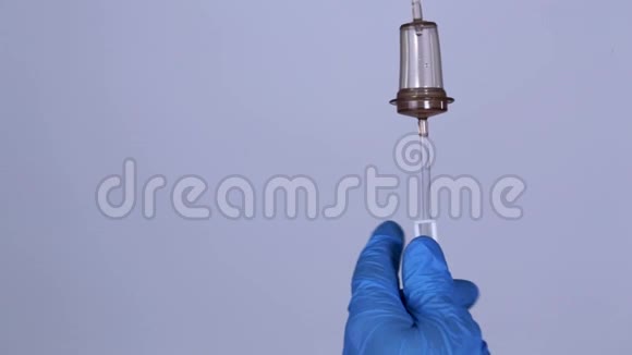 一个戴着蓝色手套的医生的手管理滴管脓液滴在滴药台视频的预览图