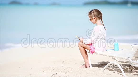 小女孩坐在日光浴床上用相机拍视频或照片视频的预览图