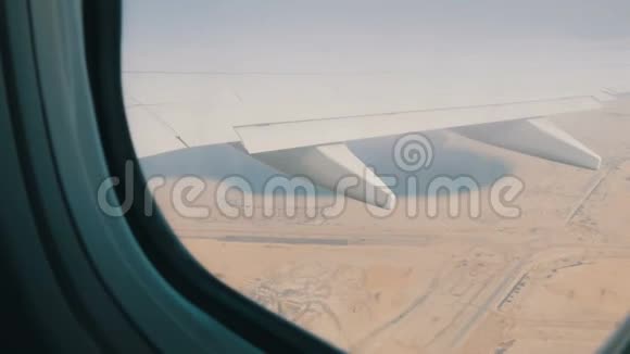 飞机正飞越沙漠在沙漠黄色景观的背景下从窗外飞过一架飞机视频的预览图