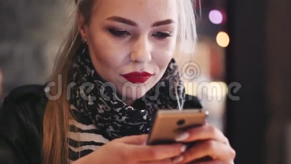 近距离观看迷人的金发女孩与自然化妆使用她的手机在线工作自由职业服务现代视频的预览图