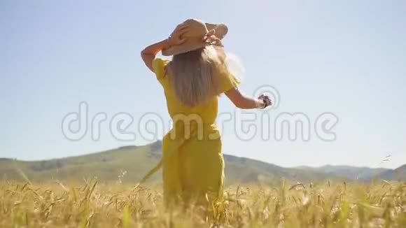 一个穿着黄色连衣裙的年轻女孩长发在麦田上奔跑慢动作视频的预览图