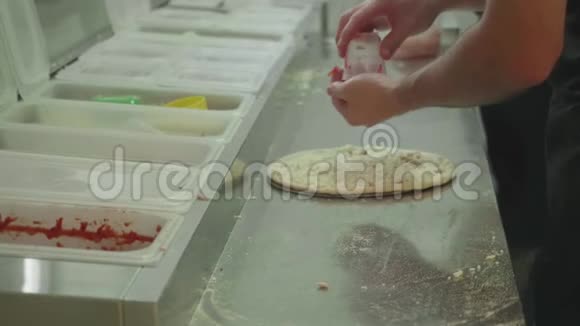 两个十几岁的孩子的手在做披萨的时候放在面团上撒番茄酱视频的预览图