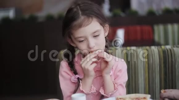 一个小女孩在餐馆吃一片披萨视频的预览图