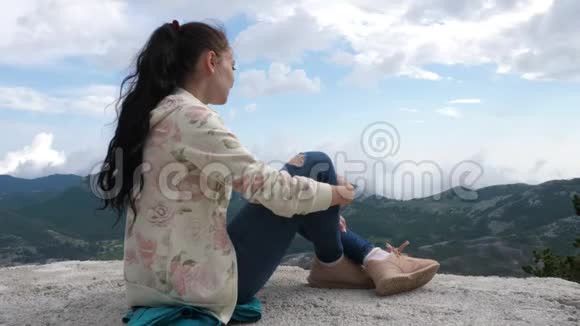 一位年轻女子欣赏山景视频的预览图