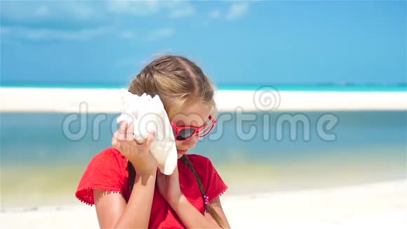 小可爱女孩在海滩上听一个大贝壳的肖像流动人口视频的预览图