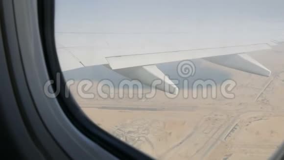 飞机正飞越沙漠在沙漠黄色景观的背景下从窗外飞过一架飞机视频的预览图