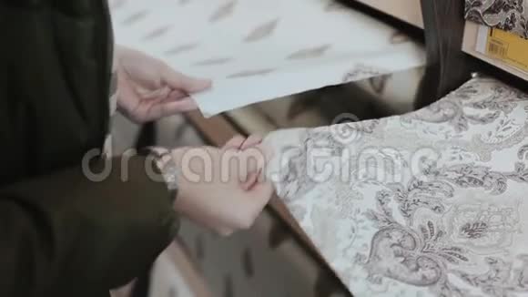 墙纸店女人的双手特写比较了她家居装饰房屋修缮室内的两种壁纸样品视频的预览图