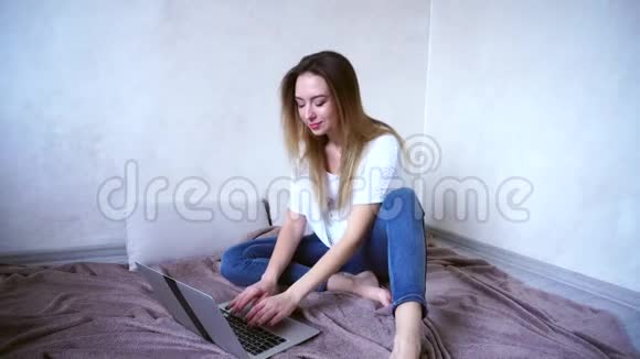 令人惊叹的年轻女性通过电子邮件使用笔记本电脑的答案并在家在线工作坐在下午的房间地板上视频的预览图