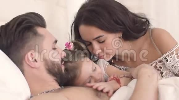 三口之家的特写母亲父亲和女儿在床上视频的预览图