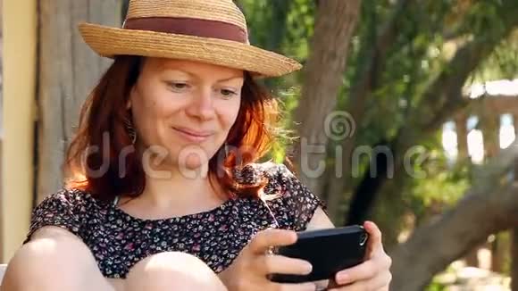 女人在花园里放松在阳光下享受她的智能手机视频的预览图