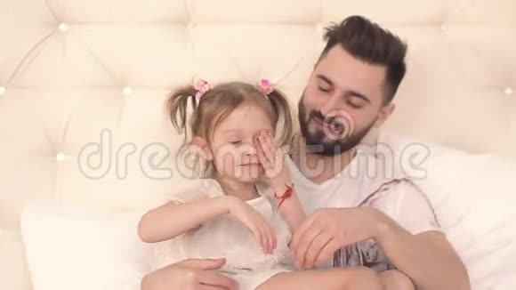 睡意朦胧的小女孩在床上拥抱父亲视频的预览图