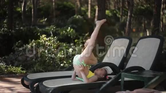 一个穿黄色泳衣的小女孩正坐在日光浴床上晒太阳视频的预览图