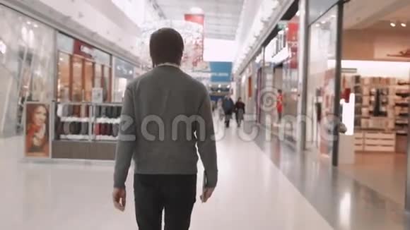 快乐的年轻人走在购物中心商店里年轻服装师的后视图视频的预览图