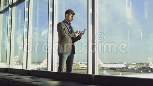 一个年轻人在机场候机大厅里用智能手机聊天视频的预览图