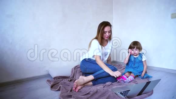 年轻的母亲和女儿使用小工具进行交流每个人都从事自己的事务坐在上面视频的预览图
