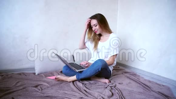 迷人的女孩坐在明亮的房间里的地板上的电脑上白天在键盘上打印文本视频的预览图