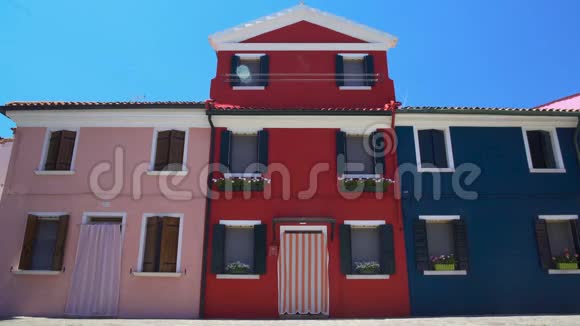 美丽的粉红色红色和蓝色的房子装饰着美丽的花朵布拉诺岛视频的预览图