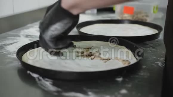 厨师准备一个披萨把配料放在面团上厨师把比萨饼和蘑菇放在上面视频的预览图