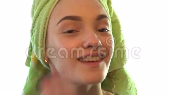 头发上有毛巾的年轻女孩微笑着做面霜视频的预览图