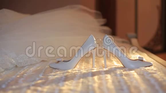 婚礼的概念订婚戒指被放置在白色时尚高跟鞋之间躺在床上背景是视频的预览图