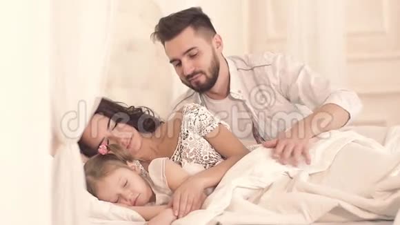 慈爱的父亲躺在床上亲吻家人视频的预览图