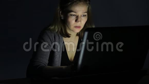 沮丧的勤劳的女人在黑暗的房间里用笔记本电脑工作视频的预览图