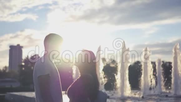 在喷泉和日落背景上亲吻一对相爱的夫妇高清1920x1080慢动作视频的预览图