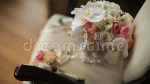 两束美丽的粉色和白色玫瑰和兰花的婚礼花束躺在古董古董椅上视频的预览图