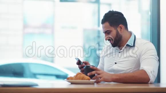 时髦的胡子男人喝着咖啡滑动着手机的屏幕现代生活交往每天视频的预览图