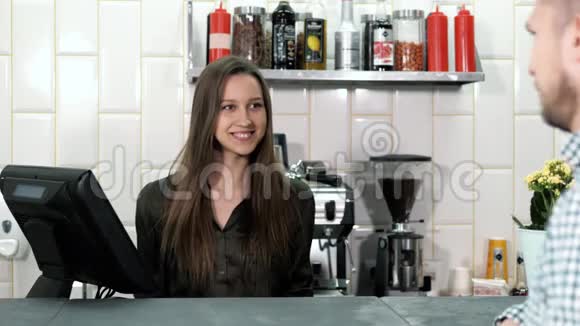 漂亮的女咖啡师从一位顾客那里点餐顾客在咖啡店里放了一个平板电脑她微笑着视频的预览图