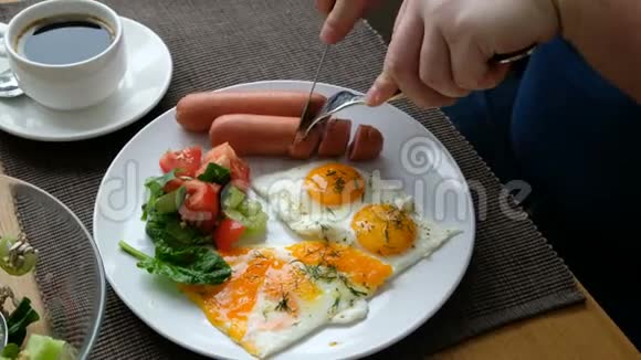 吃早餐的人刀叉在手美式早餐包括煎鸡蛋香肠沙拉和烤面包视频的预览图