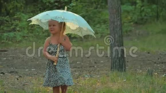 带着雨伞在森林里散步的可爱的小女孩视频的预览图