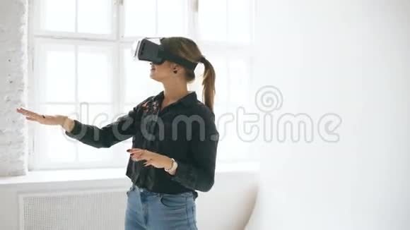 在室内的白色房间里VR耳机里的女人抬起头试图触摸虚拟现实中的物体视频的预览图