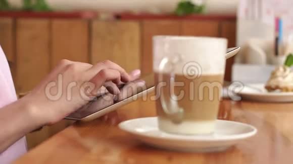 女孩在咖啡馆里拿着平板电脑和咖啡杯视频的预览图